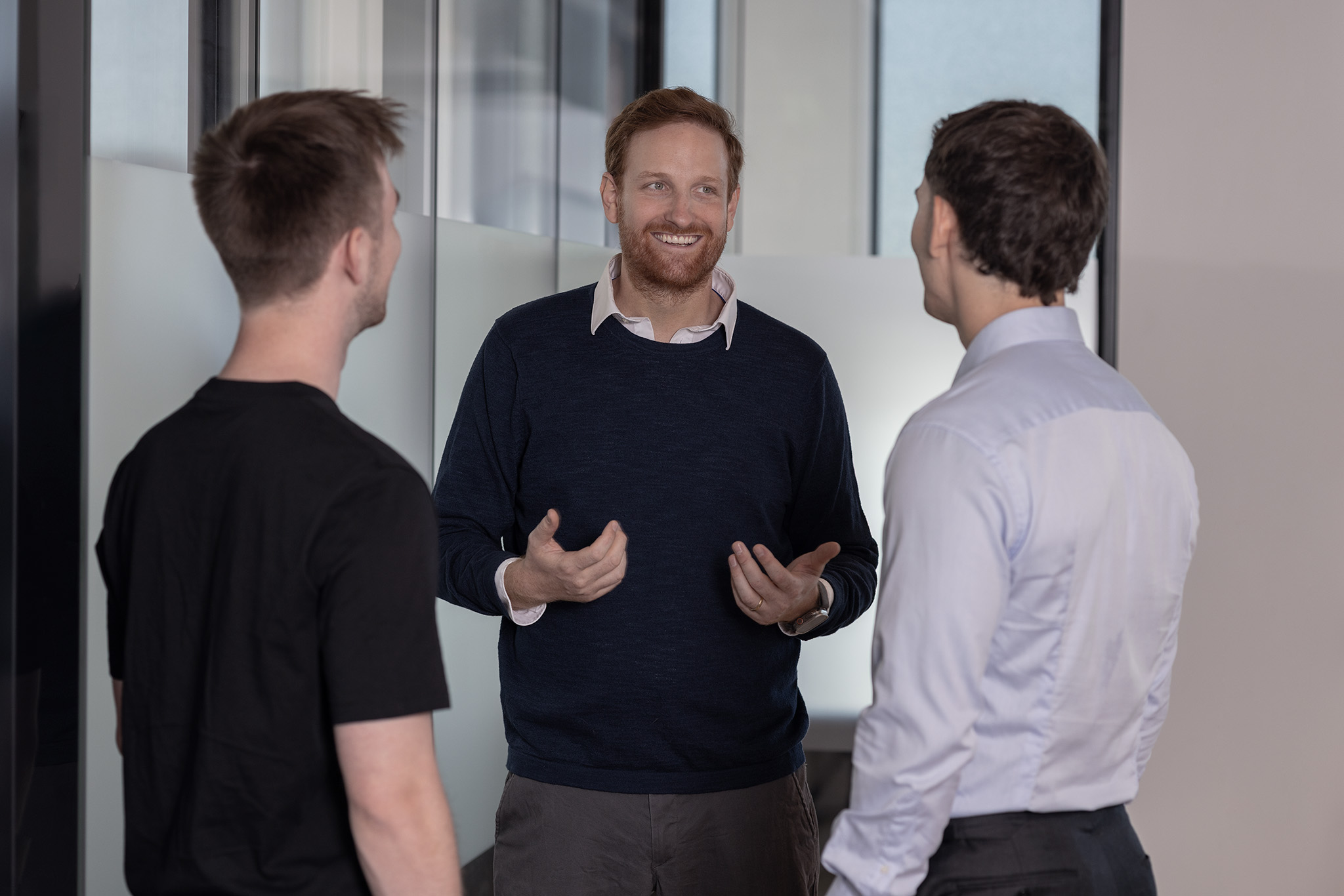 Teammitglieder des Investitionsbereichs „Venture Capital“: Drei Männer sind in einem lockeren Gespräch miteinander.