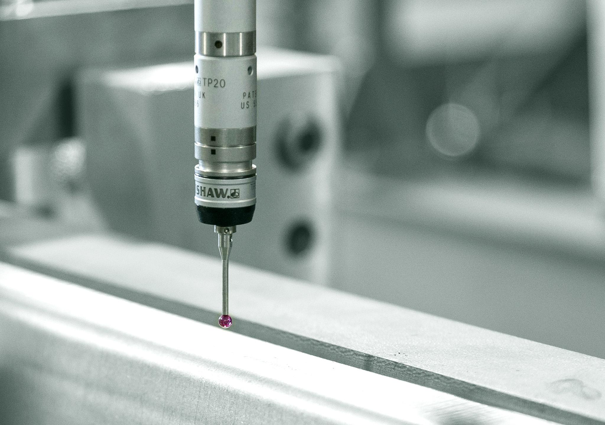 Präzisionsmessgerät mit feiner Messspitze und rotem Taster, das über einer hellen Werkstückkante positioniert ist.